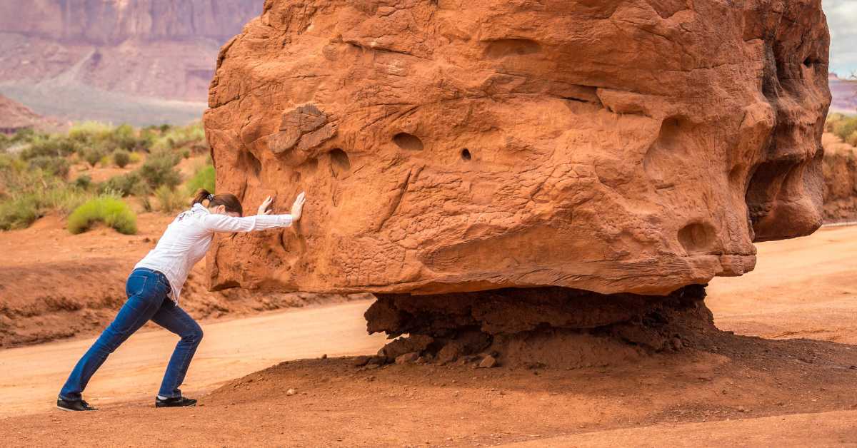 Woman pushing a large boulder