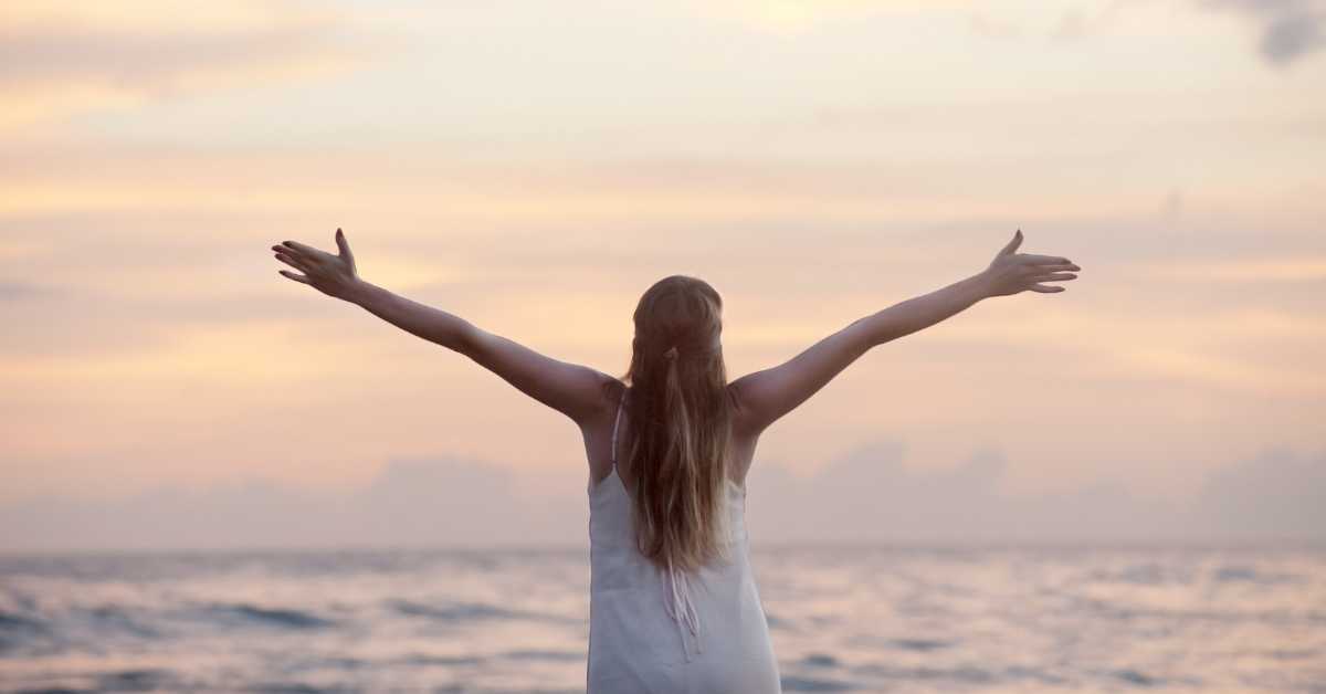 Lady looking out to the sea with her arms outstretched