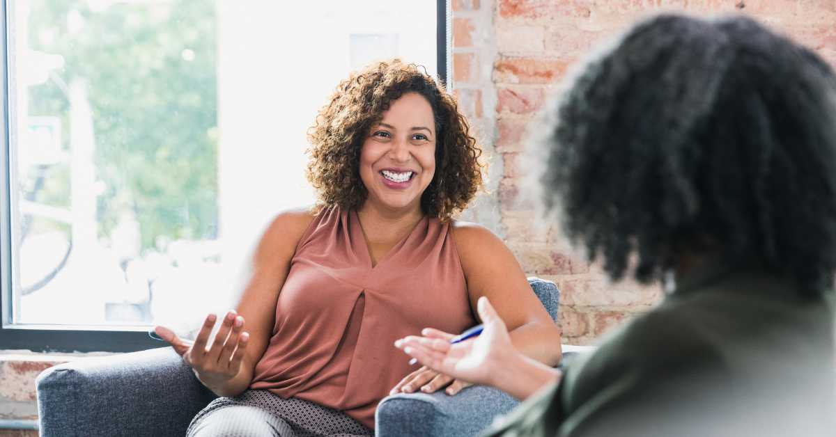 Two smart ladies sat down smiling at each other