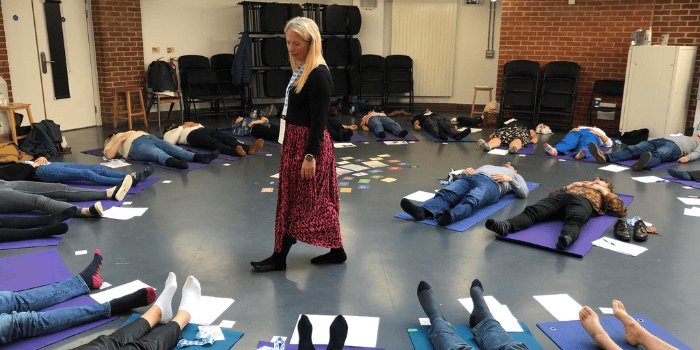 Claire Elmes running a breathwork session with participants laying blindfolded in a circle on mats.
