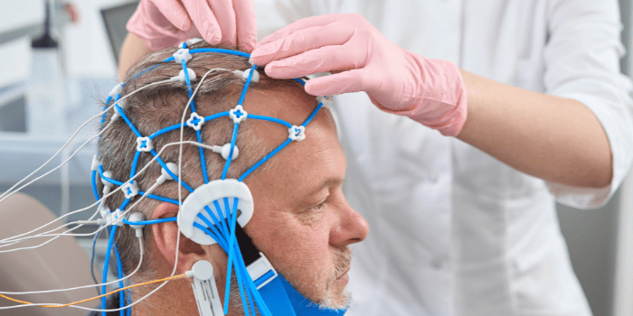 Blue electrodes on man's head during neurofeedback therapy.
