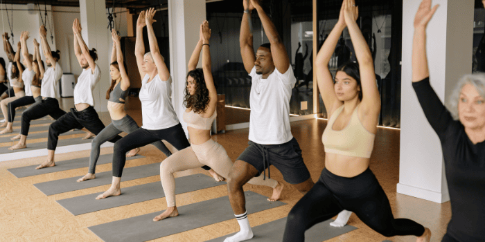 Team members performing yoga on mats in a row.